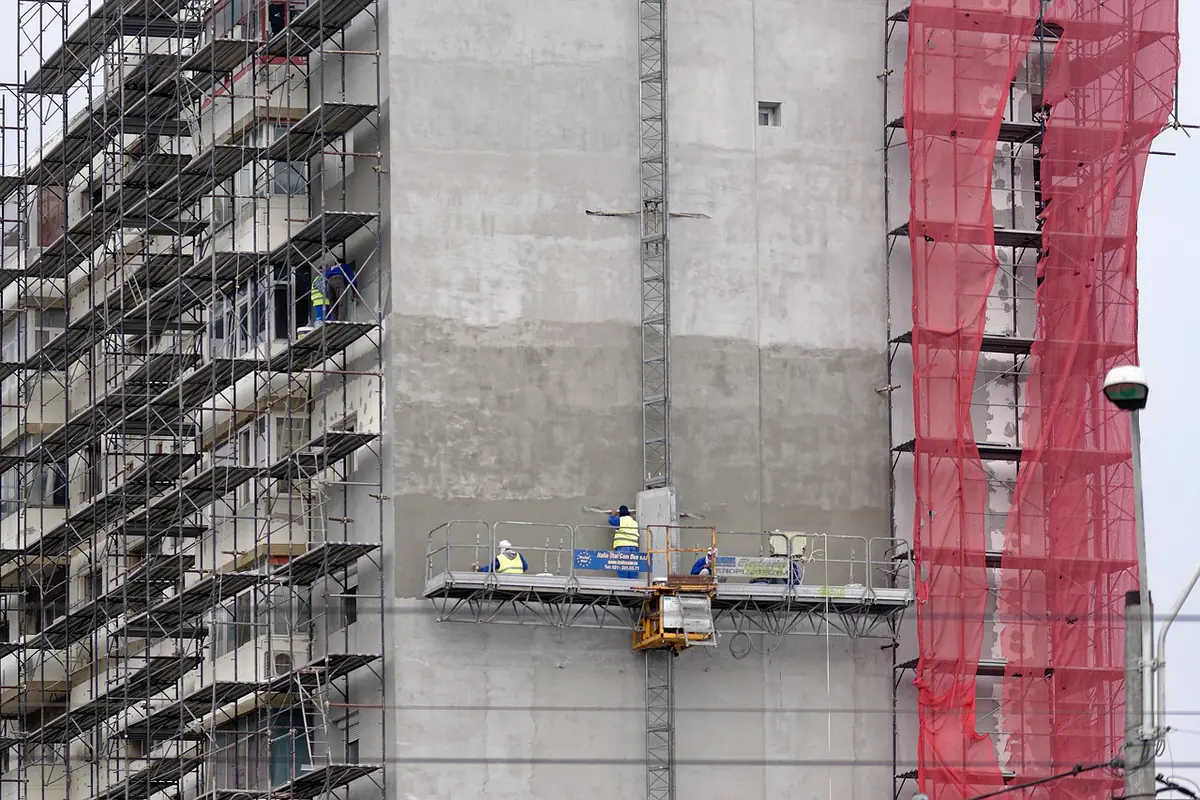 Scaffolded concrete façade with a suspended working platform during renovation
